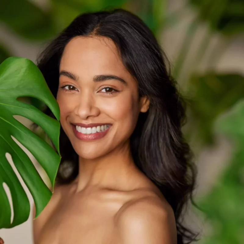 Beauty natural woman with monstera leaf looking at camera-min