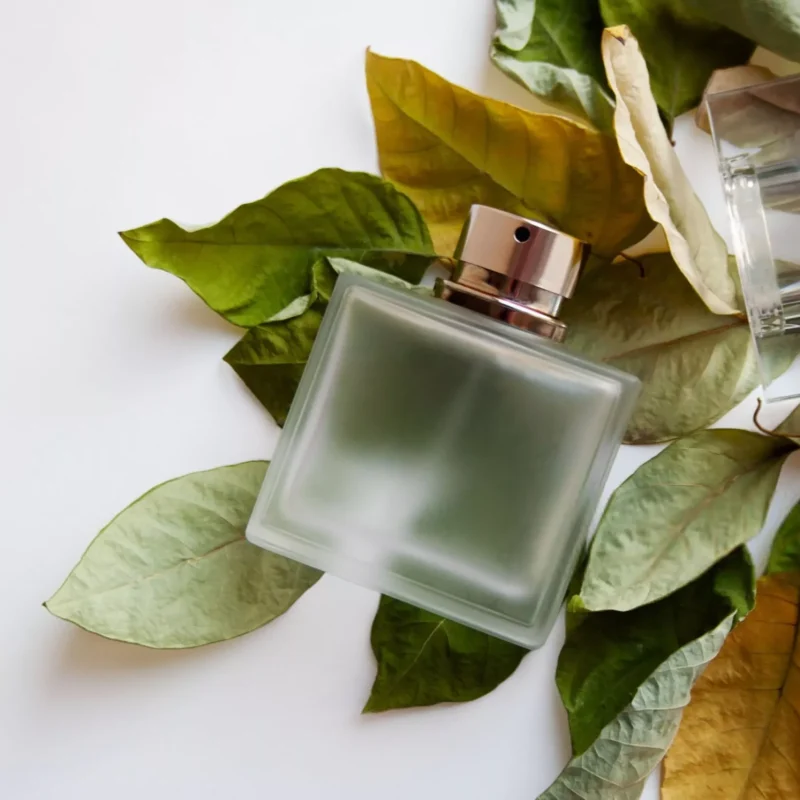 Glass-perfume-bottle-with-green-and-yellow-leaves-min-scaled.webp